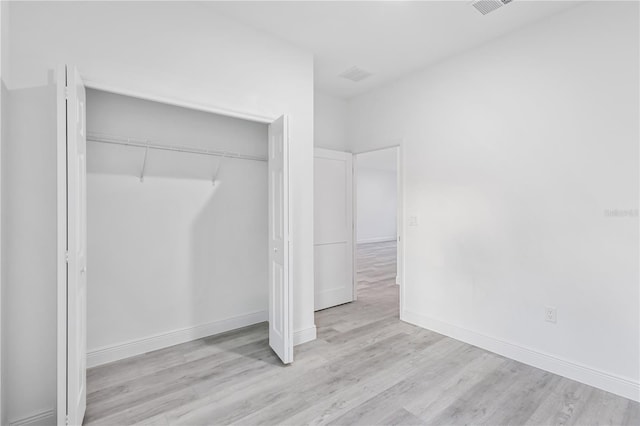 unfurnished bedroom with a closet and light wood-type flooring