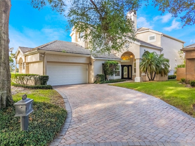 mediterranean / spanish home featuring a front yard and a garage