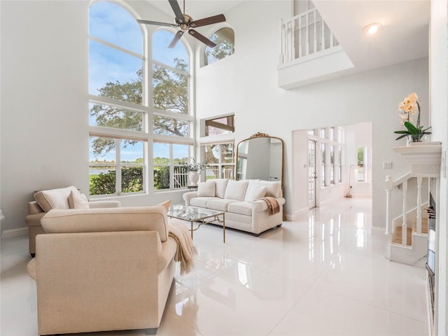 tiled living room featuring ceiling fan and a high ceiling