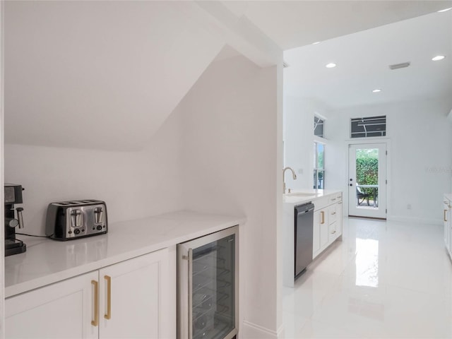 kitchen featuring sink, vaulted ceiling, beverage cooler, stainless steel dishwasher, and white cabinets