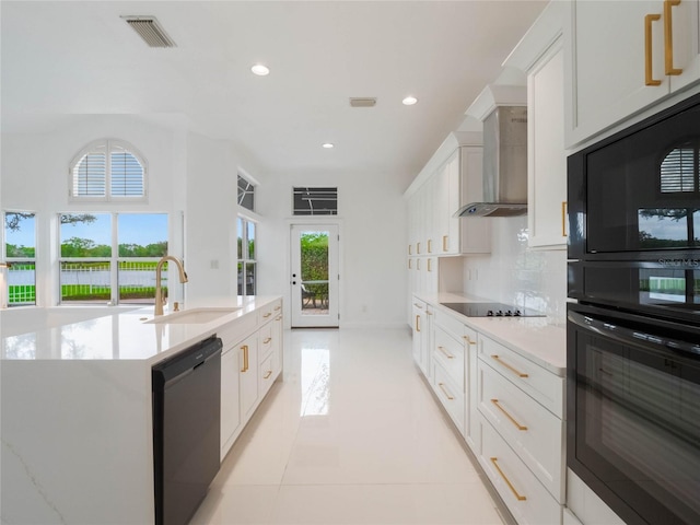 kitchen featuring sink, black appliances, white cabinetry, and wall chimney range hood