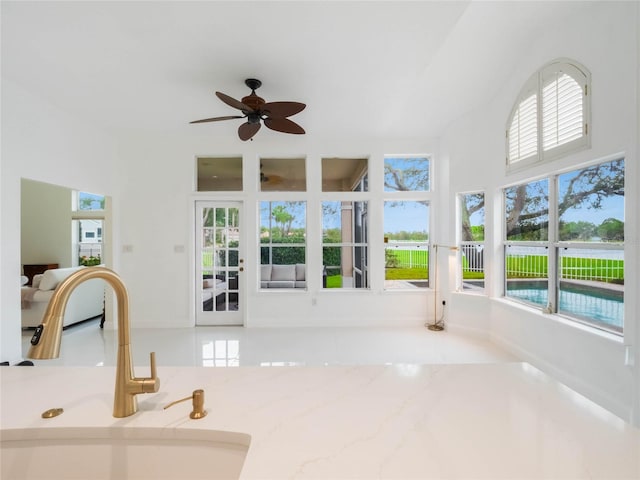 unfurnished sunroom featuring sink and ceiling fan