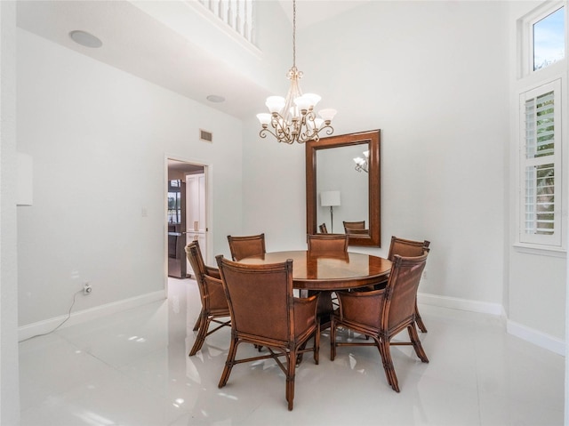 tiled dining room featuring a towering ceiling and an inviting chandelier