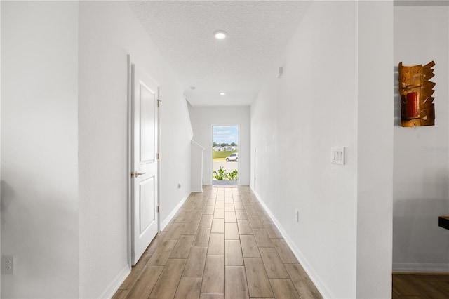 corridor featuring a textured ceiling and light wood-type flooring