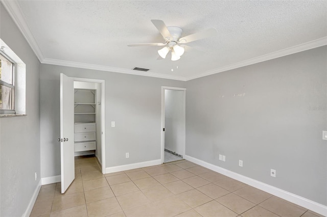 unfurnished bedroom featuring a closet, a spacious closet, crown molding, a textured ceiling, and ceiling fan