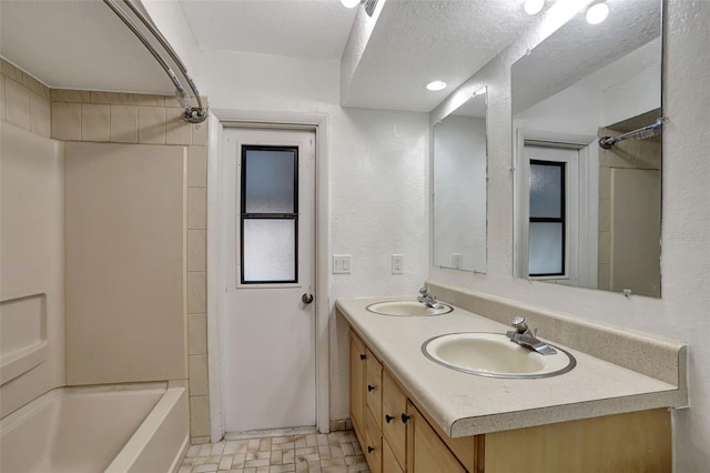 bathroom featuring vanity, shower / bathing tub combination, and a textured ceiling