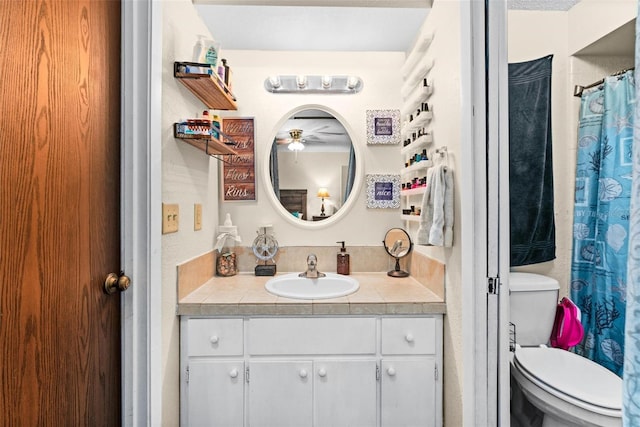 bathroom featuring toilet, vanity, ceiling fan, and curtained shower