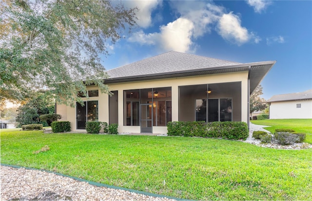 rear view of property with a lawn and ceiling fan