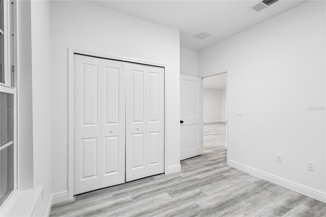 unfurnished bedroom with a closet and light wood-type flooring