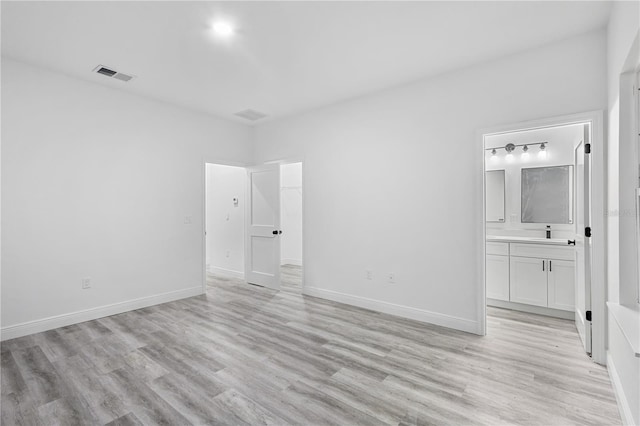 unfurnished bedroom with connected bathroom and light hardwood / wood-style flooring