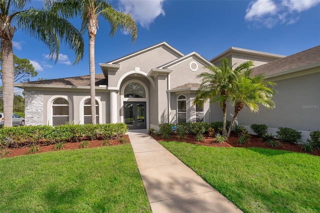 mediterranean / spanish home with a front yard and french doors