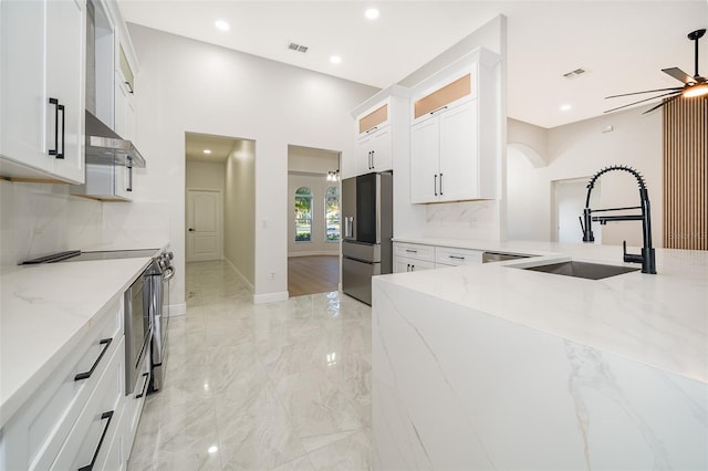 kitchen with stainless steel appliances, backsplash, sink, light stone countertops, and white cabinetry