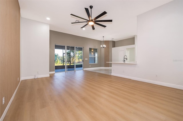 unfurnished living room featuring light hardwood / wood-style floors and ceiling fan with notable chandelier