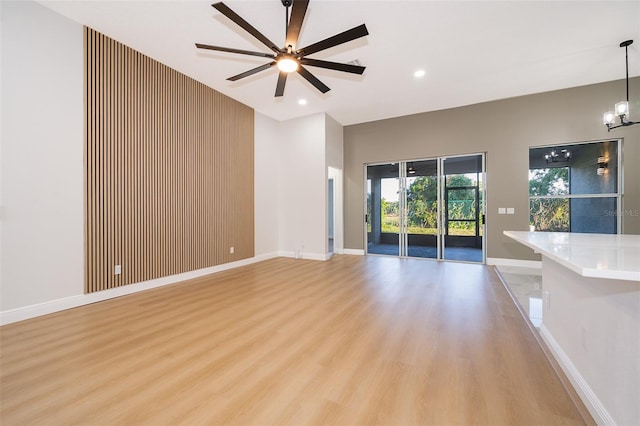 unfurnished living room with light hardwood / wood-style flooring and ceiling fan with notable chandelier