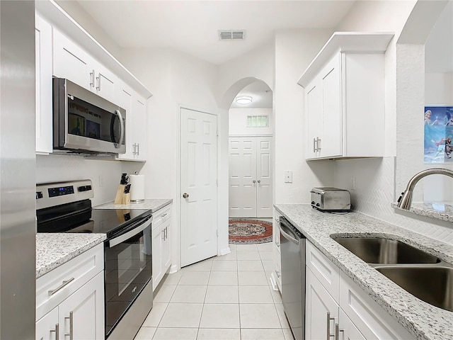 kitchen with sink, white cabinetry, stainless steel appliances, and light tile patterned floors