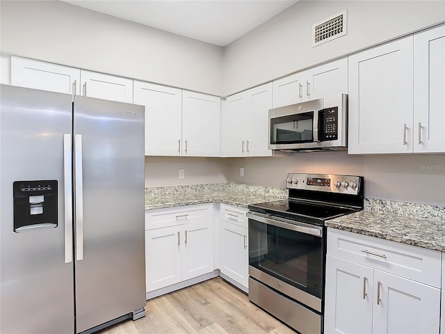 kitchen featuring light hardwood / wood-style floors, white cabinets, stainless steel appliances, and light stone counters