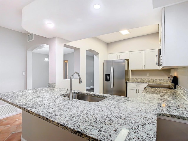 kitchen with appliances with stainless steel finishes, kitchen peninsula, white cabinets, and sink