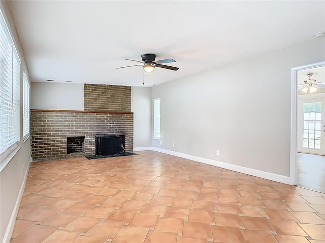 unfurnished living room with ceiling fan and a brick fireplace