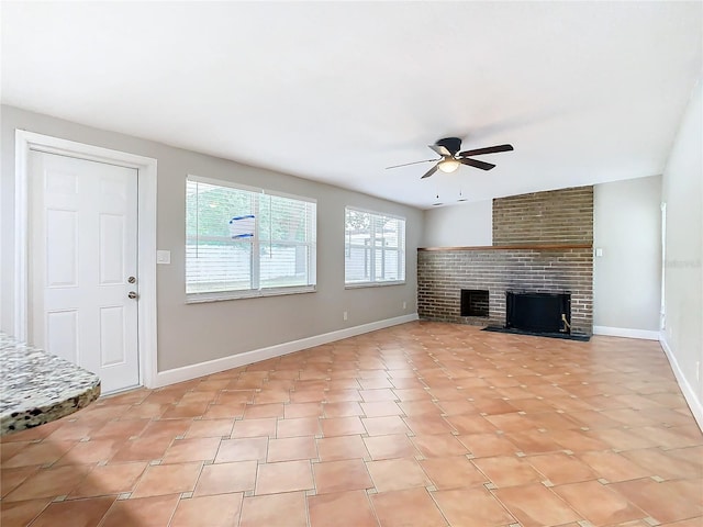 unfurnished living room with ceiling fan and a brick fireplace