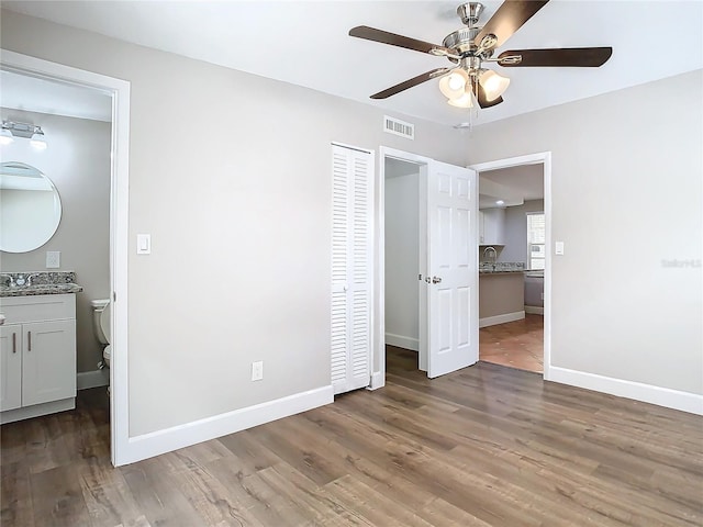 unfurnished bedroom with ceiling fan, dark hardwood / wood-style floors, a closet, and ensuite bath