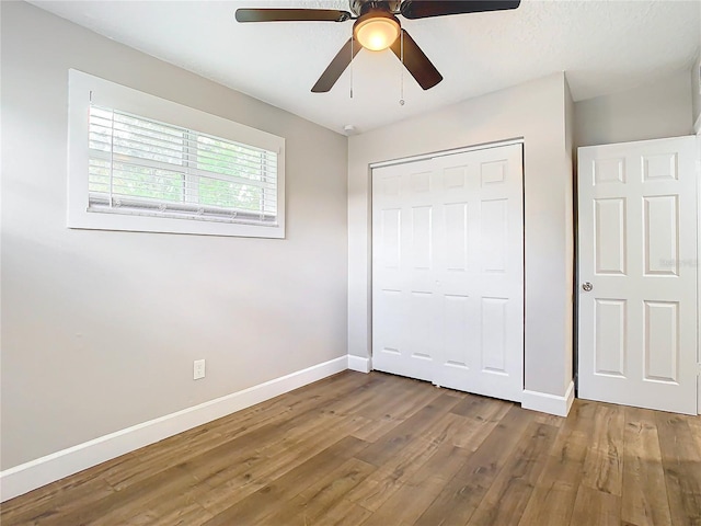 unfurnished bedroom featuring hardwood / wood-style flooring, a closet, and ceiling fan