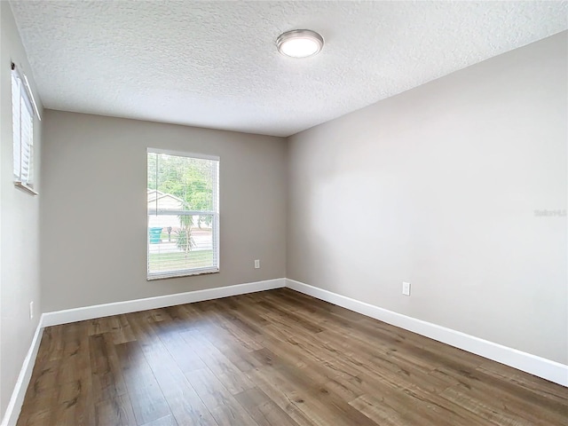 unfurnished room with dark hardwood / wood-style floors and a textured ceiling