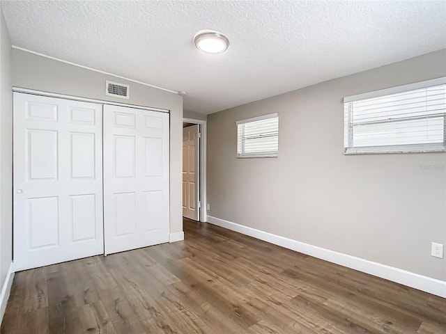 unfurnished bedroom featuring a textured ceiling, hardwood / wood-style flooring, and a closet