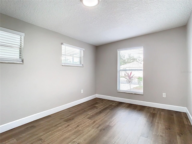 empty room with a textured ceiling and dark hardwood / wood-style flooring