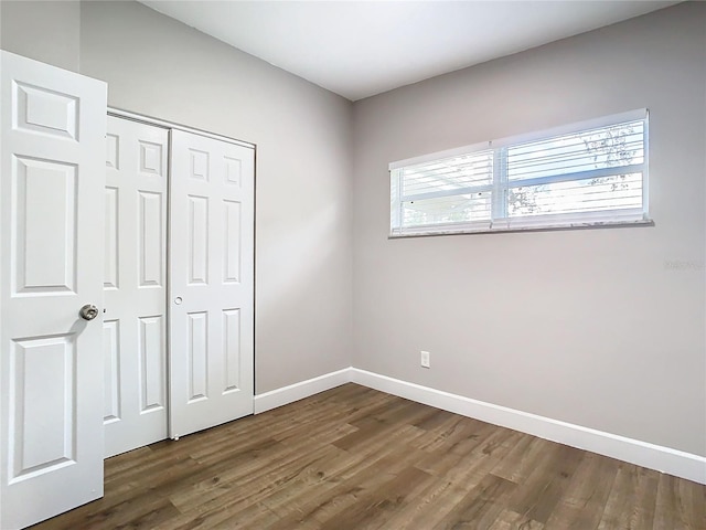 unfurnished bedroom with a closet and dark hardwood / wood-style floors