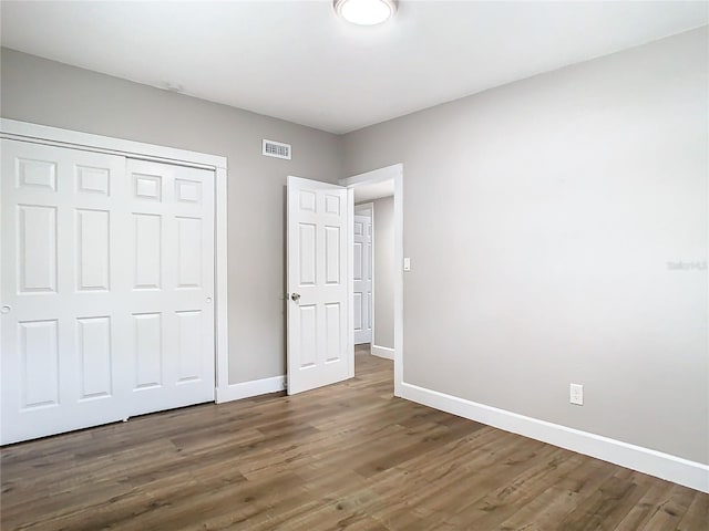 unfurnished bedroom featuring dark hardwood / wood-style floors and a closet