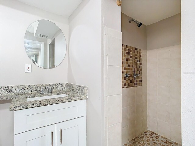 bathroom with a tile shower and vanity