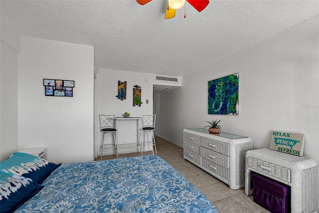 bedroom featuring ceiling fan, light tile patterned flooring, and a textured ceiling