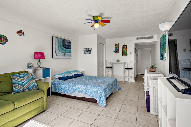 tiled bedroom with a textured ceiling, a closet, and ceiling fan