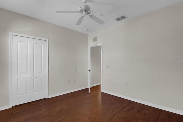 unfurnished bedroom with dark hardwood / wood-style flooring, a closet, and ceiling fan