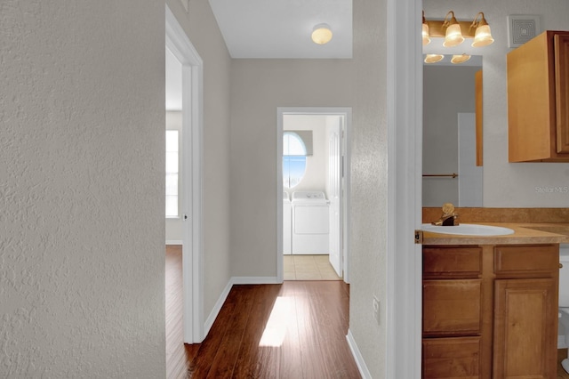 hall featuring sink, separate washer and dryer, and hardwood / wood-style floors