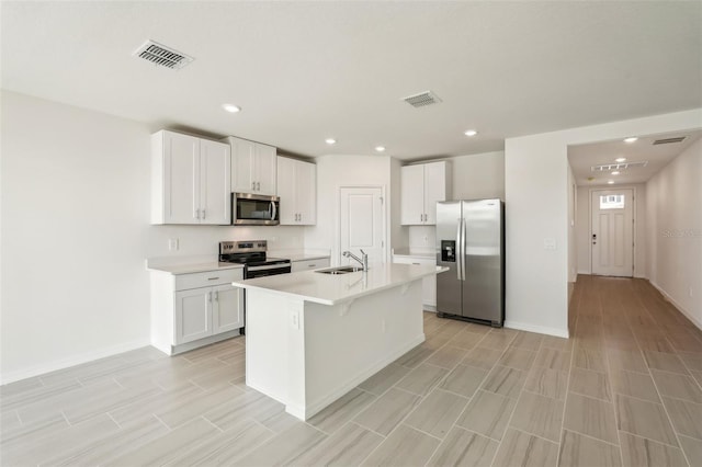 kitchen featuring a center island with sink, a kitchen breakfast bar, white cabinets, sink, and stainless steel appliances