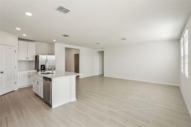 kitchen with a center island with sink, white cabinets, sink, and appliances with stainless steel finishes