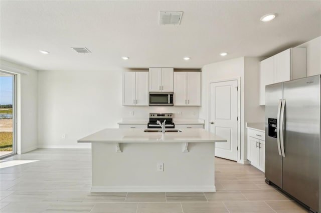 kitchen with stainless steel appliances, white cabinetry, a center island with sink, and sink