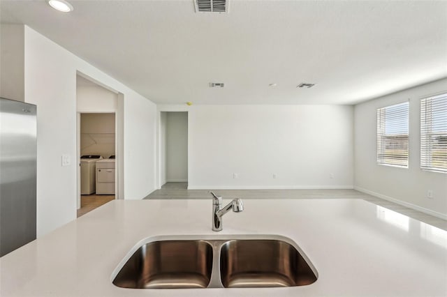 kitchen with washer and clothes dryer, stainless steel fridge, and sink