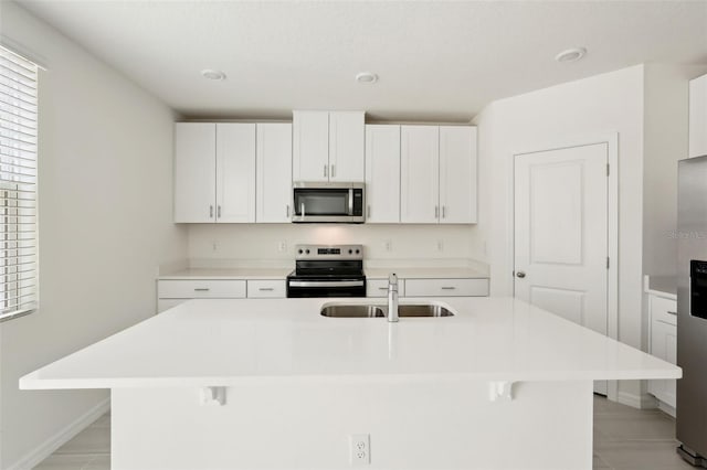 kitchen featuring a breakfast bar, a center island with sink, sink, white cabinetry, and stainless steel appliances