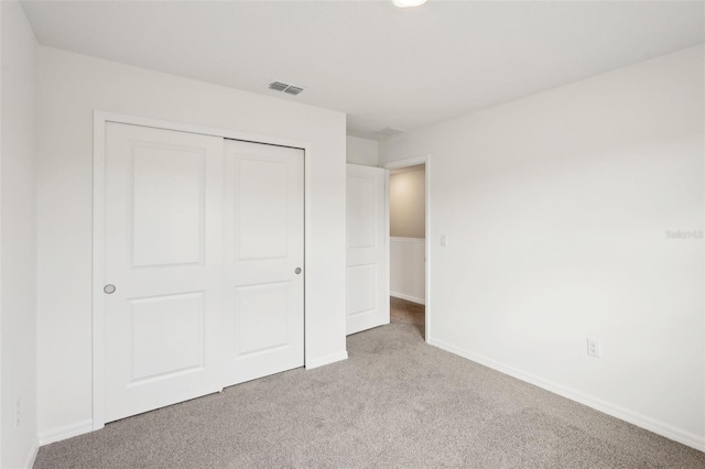 unfurnished bedroom with light colored carpet and a closet