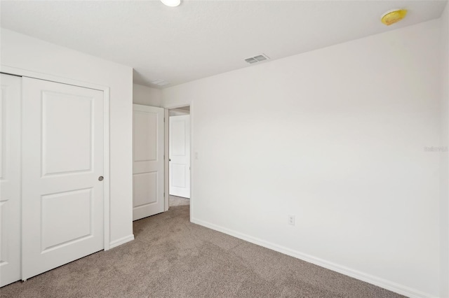 unfurnished bedroom featuring light carpet and a closet