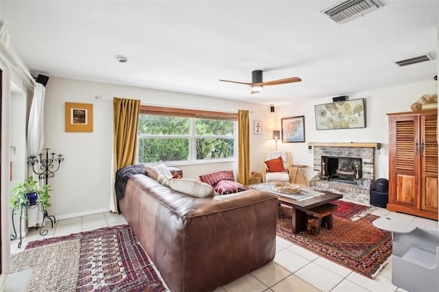 tiled living room featuring ceiling fan, a textured ceiling, and a fireplace