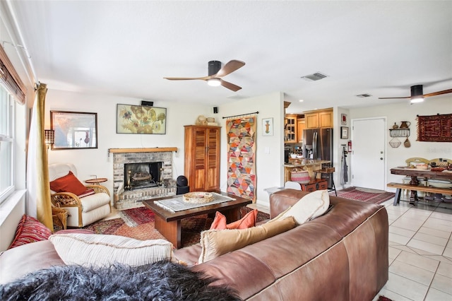 tiled living room featuring a fireplace and ceiling fan