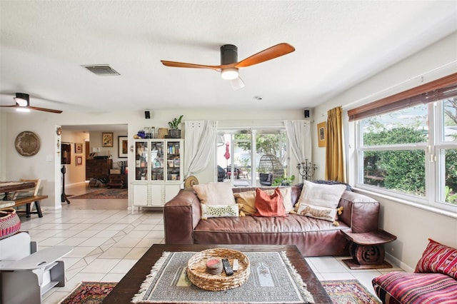 tiled living room featuring a textured ceiling, ceiling fan, and a wealth of natural light