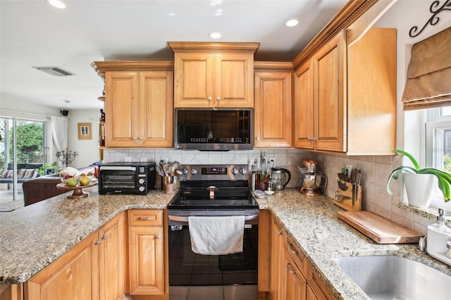 kitchen featuring sink, decorative backsplash, light stone counters, and stainless steel appliances