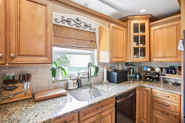 kitchen featuring black dishwasher, tasteful backsplash, light stone countertops, and sink