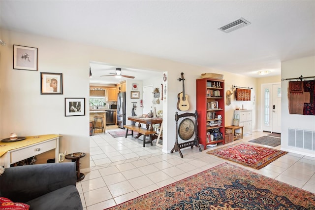 living room with ceiling fan, light tile patterned floors, and a barn door