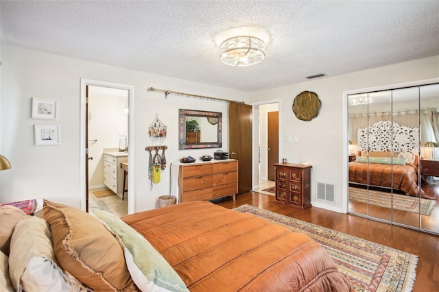 bedroom featuring connected bathroom, a closet, a textured ceiling, and hardwood / wood-style floors