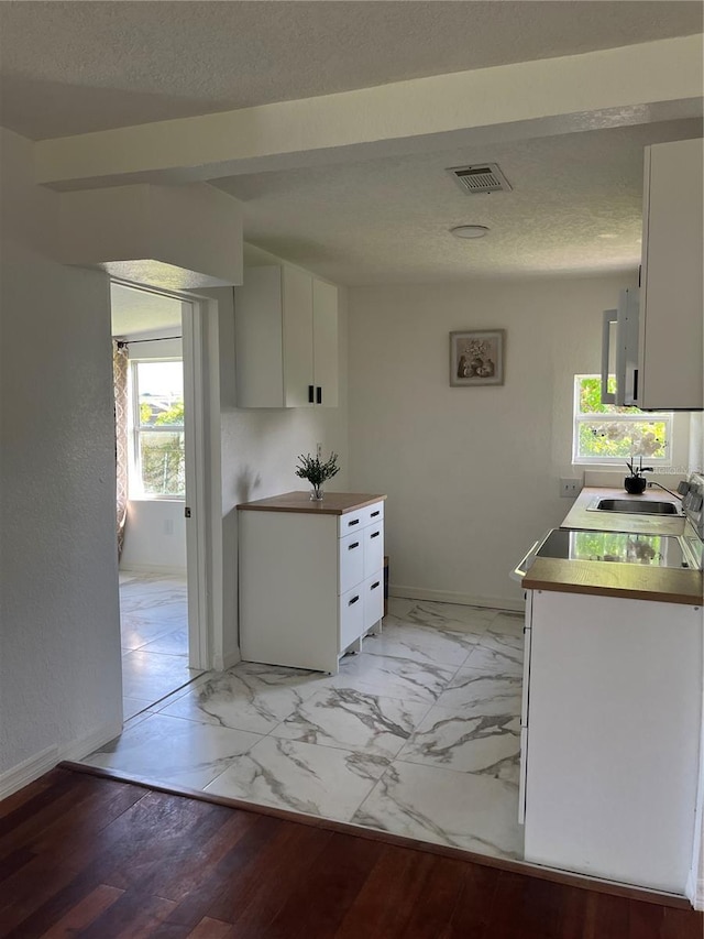 kitchen featuring light hardwood / wood-style floors, a textured ceiling, sink, and white cabinets